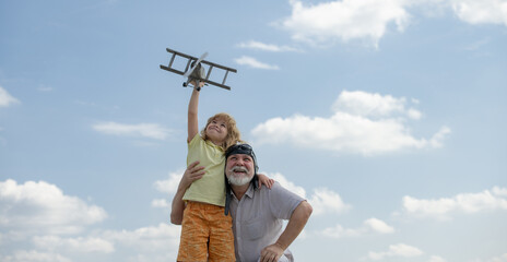 Grandfather and son with toy plane over blue sky and clouds background. Men generation grandfather and grandson playing outdoors.