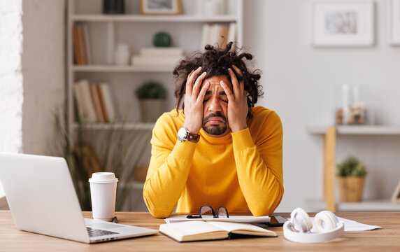 Frustrated young african american with eyes closed suffering from headache   feeling stressed with work at laptop