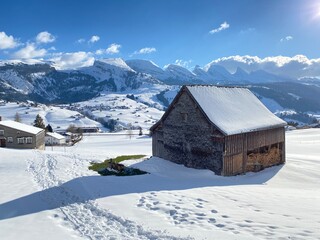 Indigenous alpine huts and wooden cattle stables on Swiss pastures covered with fresh white snow cover, Unterwasser - Obertoggenburg, Switzerland (Schweiz)