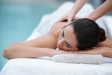 Fototapeta na wymiar Losing herself in sublime comfort. Shot of a woman enjoying a massage beside a pool.