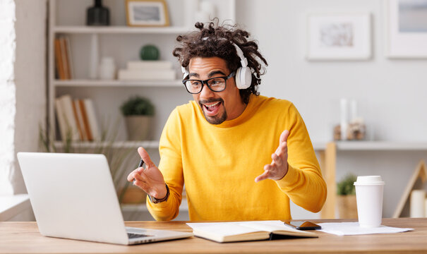 Young african american man working at laptop and talking via video call during self-isolation at home office - Powered by Adobe