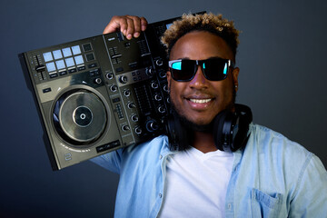 Stylish smiling black man wears black glasses and denim shirt. Popular DJ with an earring in his...
