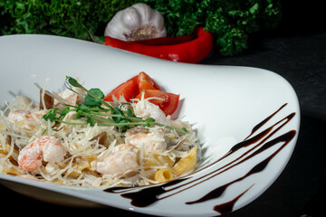 Italian pasta with shrimp and cheese. Italian pasta fettuccine on a white plate on dark background