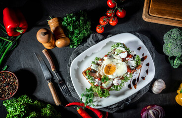 Waffle with fried egg and vegetables on dark background. Delicious traditional breakfast idea. Viennese waffles, belgian waffle recipe