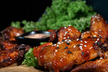 Baked chicken wings with sesame and sauce on dark background