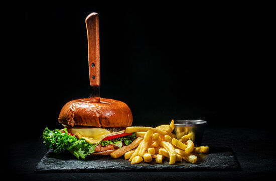 Delicious big burger with french fries on dark background