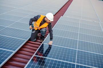 A worker kneeling and fixing solar panels.