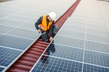 A worker installing solar panels on the roof.