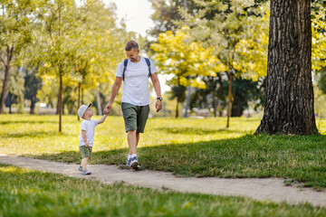 A happy father and son holding hands and walking in nature on pure air.