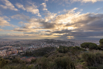Panorama of Barcelona from the air in the early morning. City with shadows from the clouds. Dramatic sky over the city. Autumn in Barcelona, Spain.