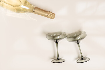 Champagne glasses tinted grey glass, Champagne or sparkling wine bottle on beige background....