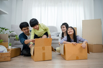 Asian family smiles and laughs happily in new home. Adorable sons and daughters play with boxes while moving house. family day activities together