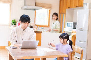 テレワークをする夫婦と子供