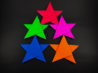 Obraz premium Abstract Defocused Five-colored star made of origami paper isolated on black background