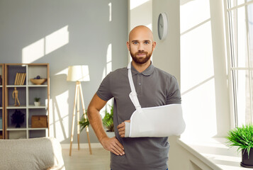 Portrait of young man with hand injury wear splint for fast recovery. Injured male with cast or sling on shoulder, have arm or shoulder trauma. Rehabilitation and healthcare concept.