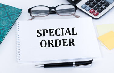 Text sign showing Special Order on notepad on a white background next to glasses, calculator, pen