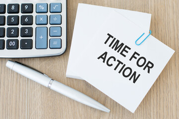 A white card with time for action text on a wooden table, a row of a calculator and a pen