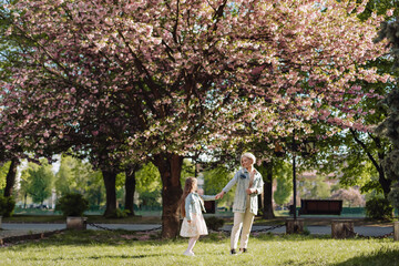 Fototapeta premium Sakura blossomed. Young mother with her child have fun in the park near the sakura. cherry trees blossom (Uzhhorod City, Ukraine)