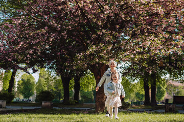 Naklejka premium Mom drives her daughter on a background of sakura in the city park