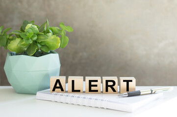 The word ALERT on wooden cubes on the desktop, a business concept