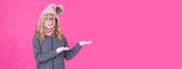 woman in winter clothes, sweater, hat, gloves and scarf pointing or showing with copy space