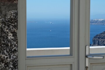 Closeup view of a door in Santorini with a breathtaking view of the Aegean Sea and the blue sky