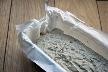 Making home bread: Fresh, home made bread before baking in the bread form on the wooden background. Bread with water, sunflower seeds, goji berries, wheat and hemp flour.   
