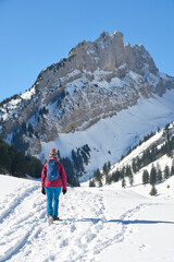 woman hiking in the snowy mountain landscape of the Alpstein mountain range near Appenzell, Switzerland