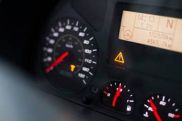 Capital T orange warning lit on speedometer of a heavy truck. Digital tachograph indicates 15 minutes left before the driver must take a brake after 4,5 hours of driving.