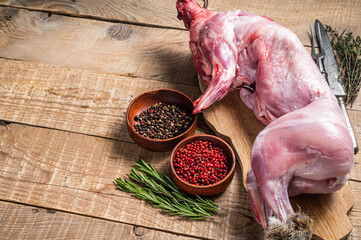 Raw Whole wild hare, fresh game meat on wooden board with herb. Wooden background. Top view. Copy...