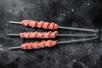Raw mince lamb meat shish kebab on butcher table. Black background. Top view