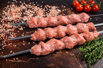 Turkish adana kebab on Skewers from Raw mince lamb and beef meat, shish kebab. Wooden background. Top view