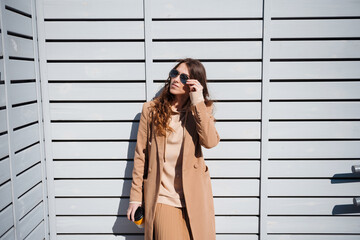 Young brunette woman in coat enjoys a cup of coffee