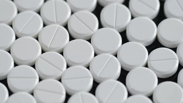 Many white round pills. Pharmaceutical production. Drugs on the production line. Moving background. close-up. view from above. white medical pills rotating closeup. Pills and drugs. Pharmaceutical