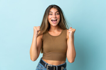 Fototapeta premium Young caucasian woman isolated on blue background celebrating a victory in winner position
