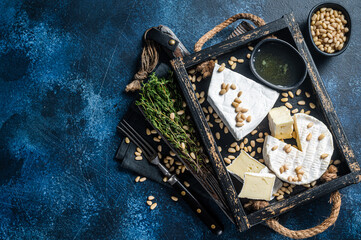 Cheese platter with brie and camembert, wooden tray with nuts. French Dairy products. Blue background. Top view. Copy space