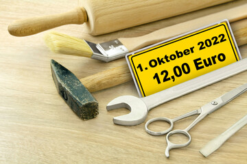 Werkzeug und gelbes Schild mit 1. Oktober 2022 und 12,00 Euro Mindestlohn in Deutschland
