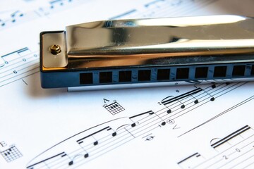 Closeup of a diatonic blues harmonica on a white page of sheet music