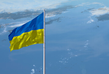 Waving Ukraine flag against a blue sky with clouds and empty space for text.