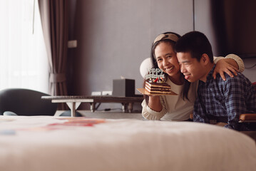 Young man with disability in surprise arranged by the parents in the bedroom,Celebrating a small birthday party with family at home, Happy life,mental health care for people with disabilities concept.