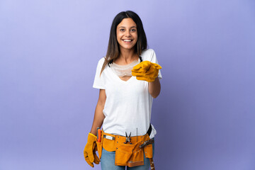 Young electrician woman isolated on purple background surprised and pointing front