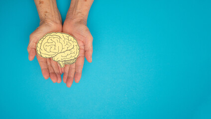 Brain shape made from paper on a palm senior woman on a blue background