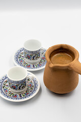 Turkish coffee in a clay pot on a white background. Traditional Turkish cuisine flavor. close up
