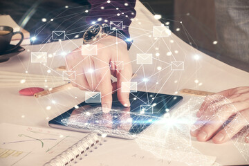 Double exposure of man's hands holding and using a digital device and envelop hologram drawing....