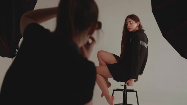 Woman photographer photographing model in studio