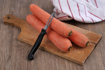 Carottes crues sur une planche à découper avec un épluche légume