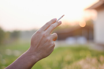 male hand holding a cigarette in a public place