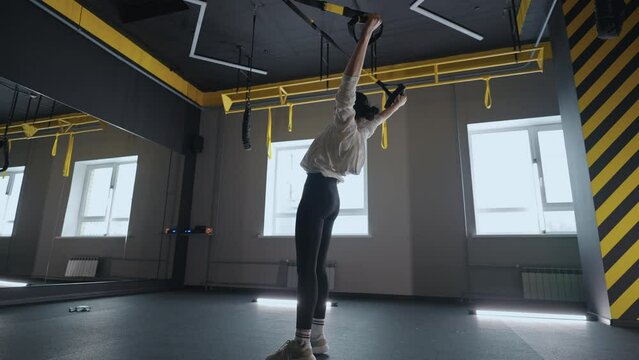 Fitness woman workout exercise with trx equipment in the fitness gym healthy lifestyle building strong and fit body. Attractive woman doing core abs crossfit training with fitness straps in the gym