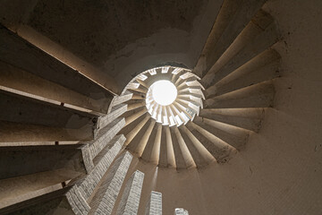 Spiral staircase with steps, upward view of a skylight, in beige tones