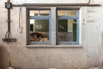 Fototapeta na wymiar Wall with two windows of a public accessible factory hall, view of chaos